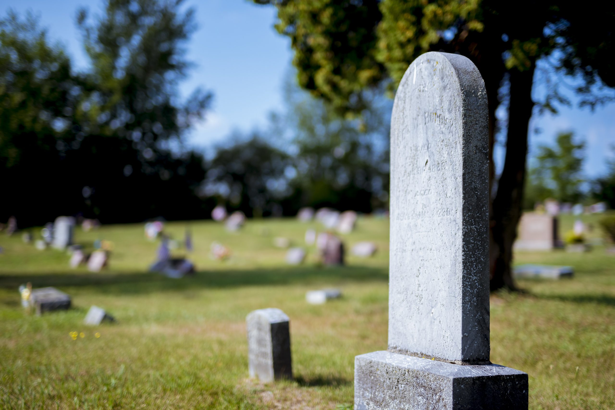 A closeup shot of a gravestone with a blurred background at daytime